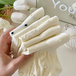 Detail von cremefarbenen Socken mit weißen Perlen und schwarzem Polka-Dot-Saum