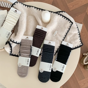 Close-up of four pairs of warm wool socks with wavy frill edges in neutral earthy colors
