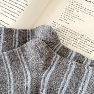 Close-up of gray and blue striped knit socks with ribbed texture on an open book