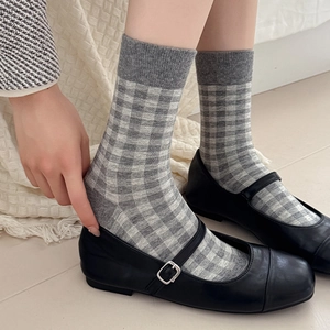 Detail of gray checkerboard pattern socks paired with black Mary Jane flats