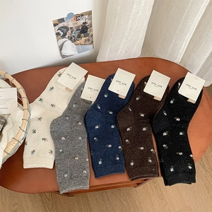 Detailed view of floral embroidery on five pairs of warm wool socks in vintage colors