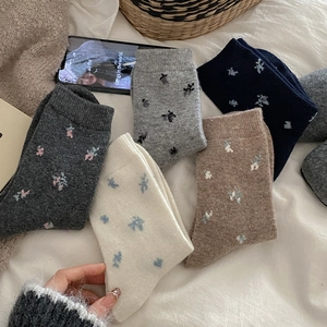 Close-up of five pairs of floral wool socks in assorted colors on soft fabric