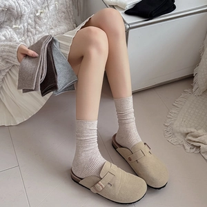 Detailed view of grey ribbed slouch socks paired with beige buckle clogs for autumn style