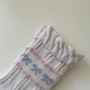 Nahaufnahme von Fair-Isle-Wollsocken mit Rüschenrand und rosa Strickwellenmuster