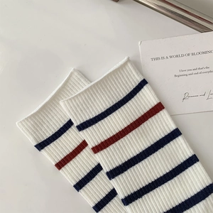 Detail of white ribbed knit socks with navy and maroon horizontal stripes in college style