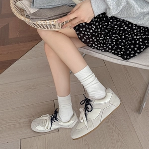 Detail of cream leather patchwork sneakers paired with white ribbed mid-calf crew socks