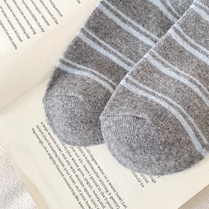 Close-up of thick knitted grey socks with light blue stripes on vintage book pages