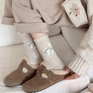 Gros plan de mules en daim marron avec doublure polaire et chaussettes à motif de chat
