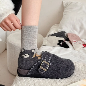 Detail of wool clogs with metal buckle paired with cartoon bear pattern crew socks