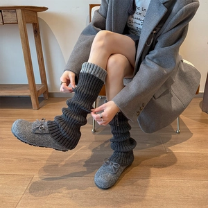 Détail de jambières en maille gris foncé portées avec des mocassins à nœud gris