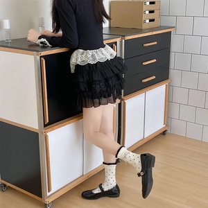 Detail weißer gepunkteter Socken mit Spitzenbesatz und schwarzen Mary Jane Schuhen