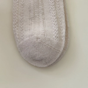 Detail von cremeweißen Wollsocken im Fair-Isle-Stil mit filigranem Strickmuster