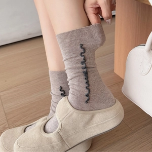 Detailed view of taupe wool socks with black ruffled texture styled with cream loafers