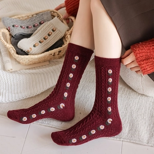 Close-up of burgundy wool socks featuring vintage cable knit and daisy flower embroidery