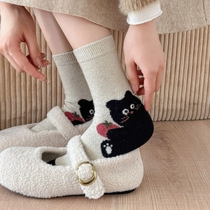 Close-up of thick winter wool socks with cute black cat and strawberry cartoon patterns