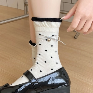 Detail weißer Socken mit schwarzen Punkten, Rüschenrand und Herz-Charm-Schleife