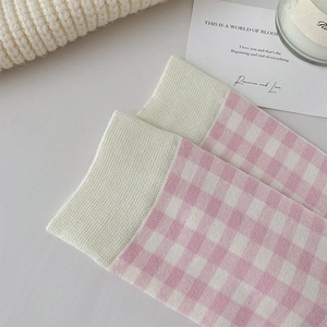Detail of pink and white checkered mid-calf socks with ribbed cuffs in a soft knit