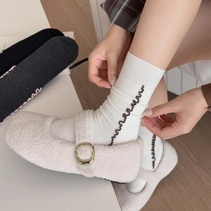 Detail of white fleece Mary Janes with gold buckle and wave-patterned cotton crew socks