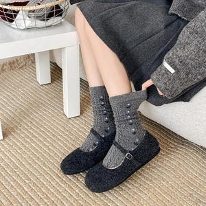 Detail view of grey cable-knit wool socks with blue floral embroidery and Mary Jane shoes