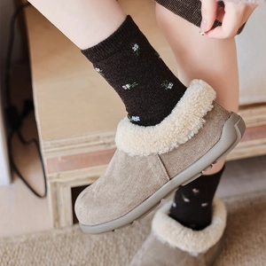 Close-up of winter mule slippers with faux lamb wool lining and floral knit socks
