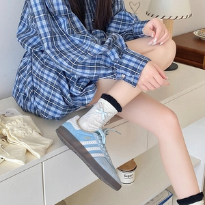 Detail von blauen Wildledersneakern mit weißen Spitzensocken und hellblauer Schleife