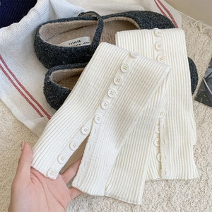 Close-up of white ribbed knit leg warmers with button detail and grey plush shoes