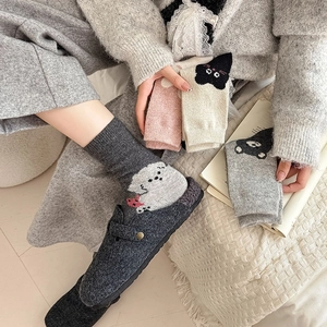 Close-up of thick knitted wool socks featuring cute cartoon animal patterns for winter
