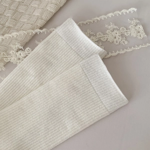 Detail shot of white cotton mid-calf socks with vertical ribbed texture and soft finish