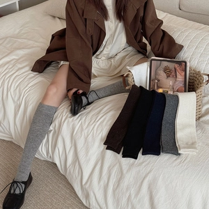 Detail of knitted mid-calf socks in various earthy colors shown in a cozy home setting