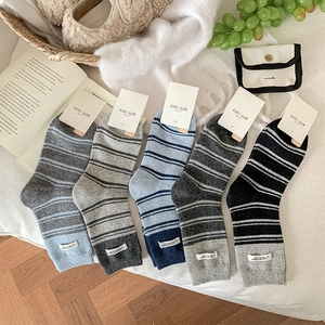 Detail of five pairs of warm striped crew socks with knit texture on a soft white rug