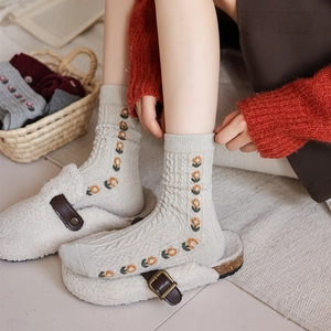 Detail of cable knit wool socks featuring retro floral embroidery for winter warmth
