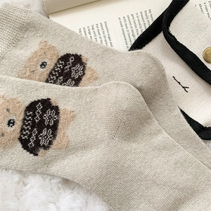 Close-up of cozy knitted beige wool socks with cute brown flocked bear patterns