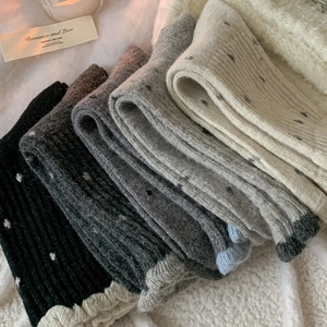 Close-up of five pairs of wool blend polka dot socks in gradient grey and black shades