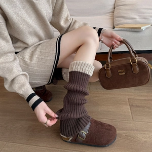 Détail de jambières en tricot côtelé marron café avec revers contrasté beige et mules en daim