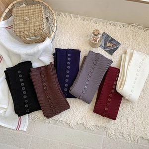 Close-up of ribbed knit leg warmers with side buttons in multiple classic colors