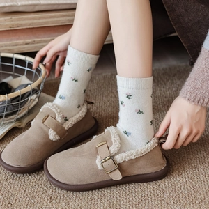 Brown suede mules with faux shearling lining and floral socks in a warm home setting