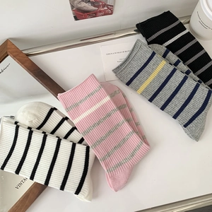 Detailed close-up of four assorted colorful striped cotton crew socks on a white desk