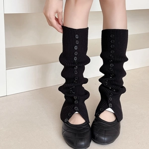Close-up of black ribbed knit leg warmers with button slit detail and quilted leather shoes