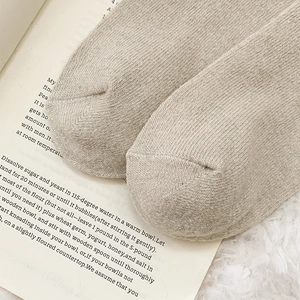 Close-up of fine knit toes on beige wool socks with a cozy plush background