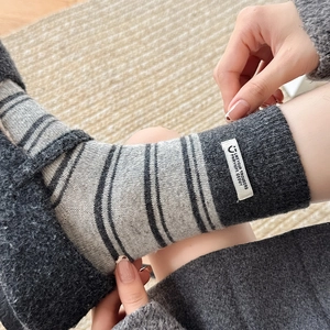 Detail of warm striped crew socks with stitched fabric label on soft carpet