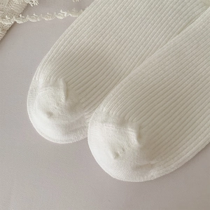 Macro detail of white ribbed cotton socks showing seamless toe and vertical knit texture