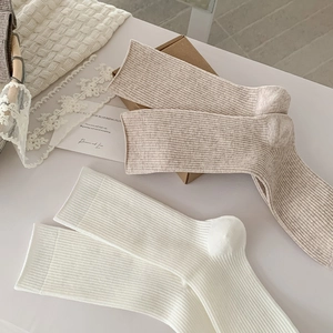 Detailed macro of beige and white ribbed knit socks in a cozy minimalist setting