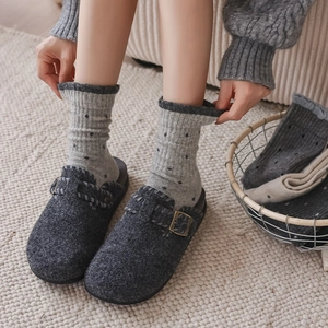 Detailed view of grey wool clogs with adjustable buckles and polka dot socks