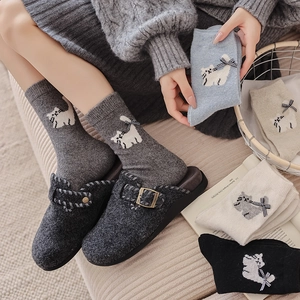 Close-up of wool socks with cat patterns and bow ties paired with felt mule slippers