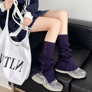Detail of dark purple ribbed knit leg warmers featuring decorative side buttons