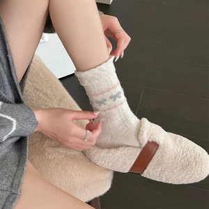 Nahaufnahme von Fair Isle Wollsocken mit rosa Schleifen und Plüsch-Hausschuhen für Damen
