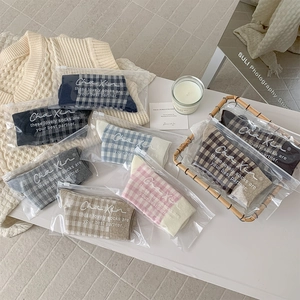 Detail of plaid crew socks in zipper bags with aesthetic knits and candles backdrop