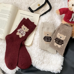 Detail of wool socks with flocking bear embroidery on cozy white plush background