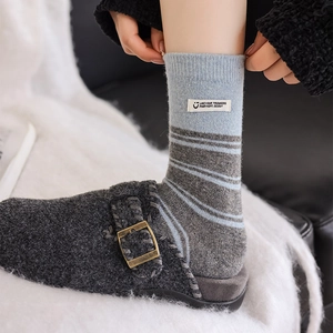 Macro shot of striped thermal socks with cloth labels and metal buckle felt mules
