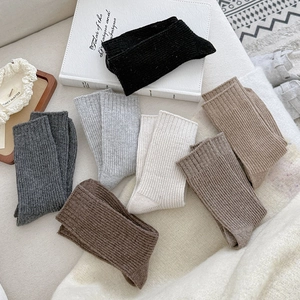 Texture detail of rib knit wool socks in earthy tones laid on a cozy white surface